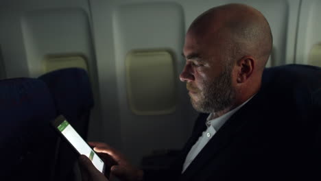 Hombre-Maduro-Trabajando-En-Una-Tablet-Pc-En-Un-Vuelo-Nocturno-En-Un-Avión-Comercial