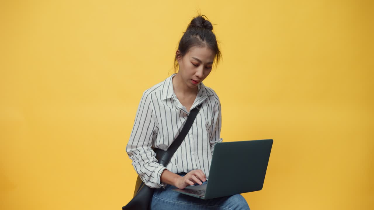 행복한 아름다움 아시아 청소년 캐주얼 소녀 타이핑 노트북 컴퓨터 스탠드 오버 고립 노란 빈 공간 배경 미소로 카메라를보고 광고를 발표하는 표지판을 주십시오 미소.