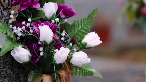 Cemetery-flowers-moved-by-the-wind-on-a-rainy-day,-background-out-of-focus