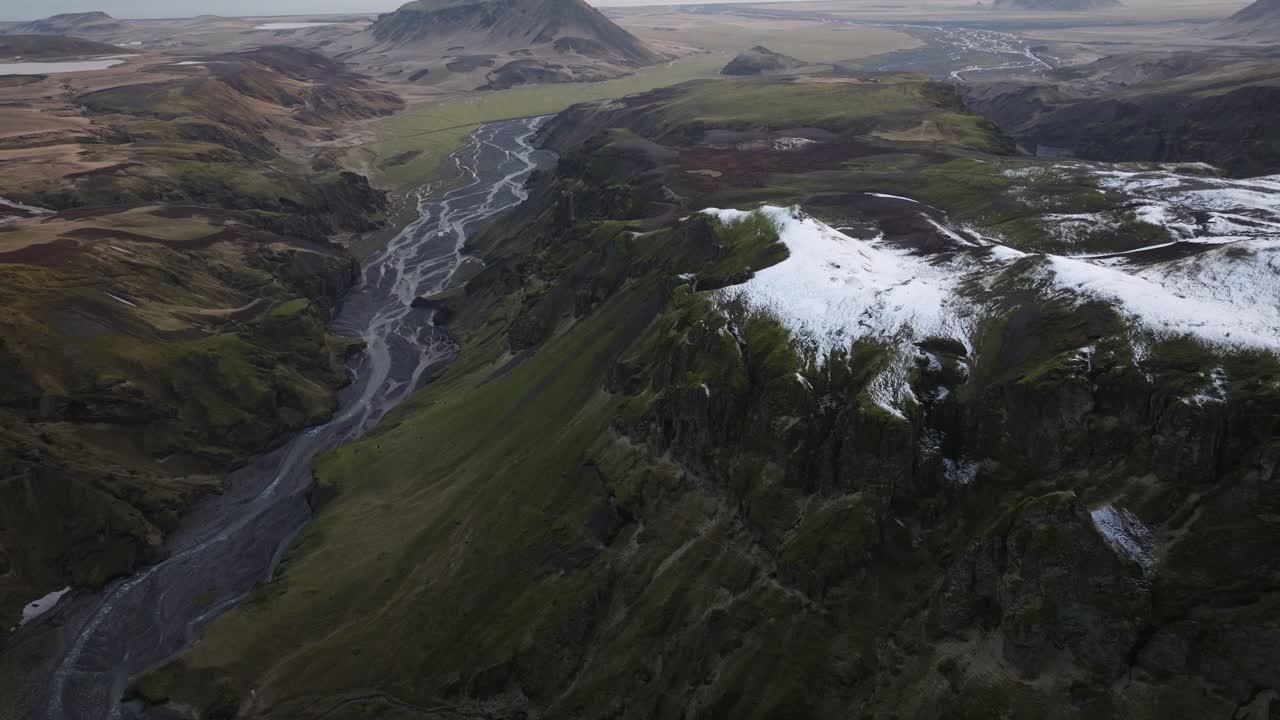 vista de un río que serpentea a través de un profundo desfiladero con colinas cubiertas de nieve en búrfell, islandia, que muestra diversos paisajes y terrenos escarpados
