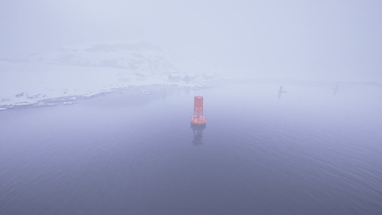 Floating buoy surrounded by dense fog on a cold day in a northern location