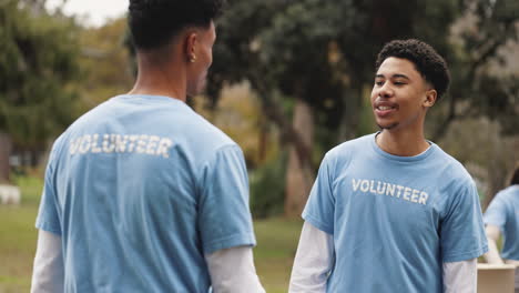 two young men volunteers smiling and shaking hands in a park