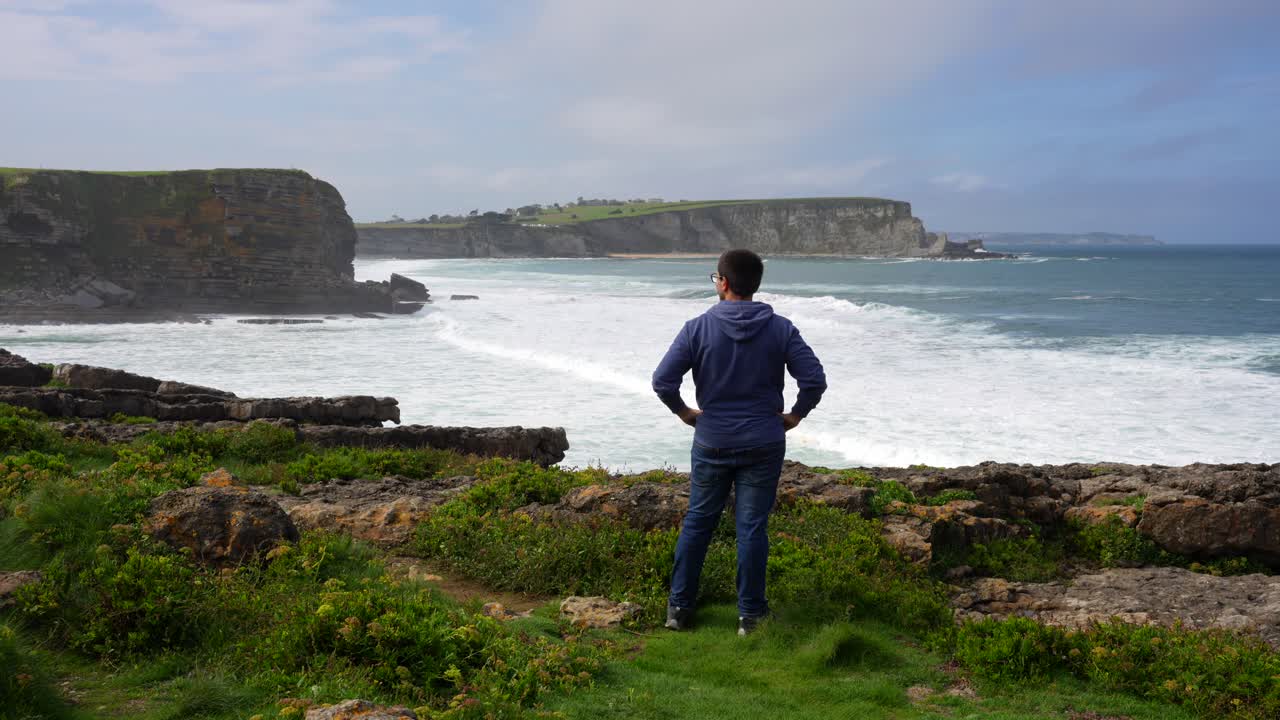 Man contemplating the vast ocean from a clifftop