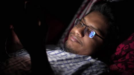 man lying in bed using a tablet at night