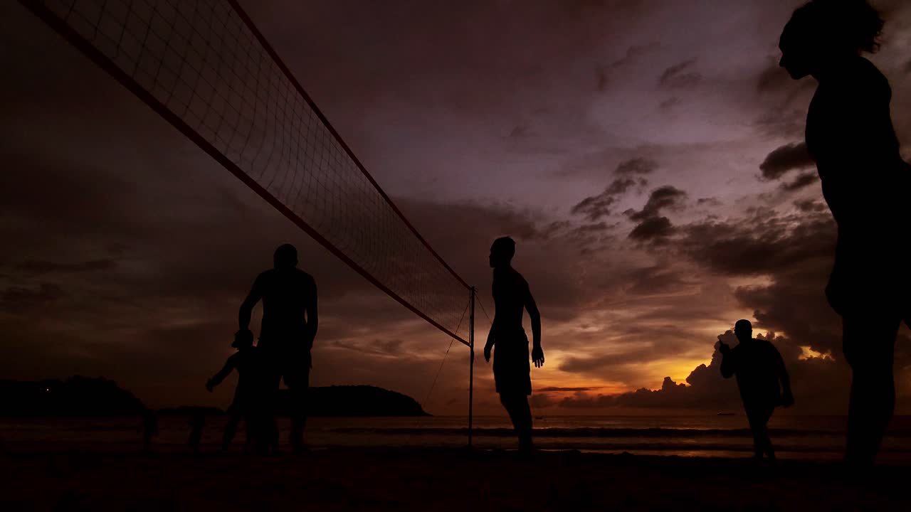 Silhouetted volleyball game at sunset on the beach