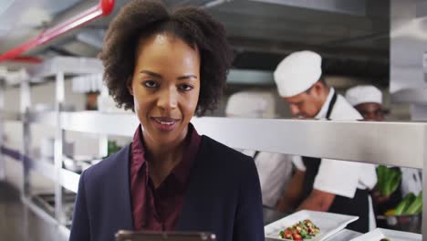 portrait of african american female manager using tablet in restaurant kitchen