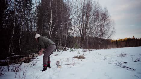 A-Man-Bears-a-Log-Upon-His-Shoulder-Amidst-a-Snowy-Scene---Static-Shot