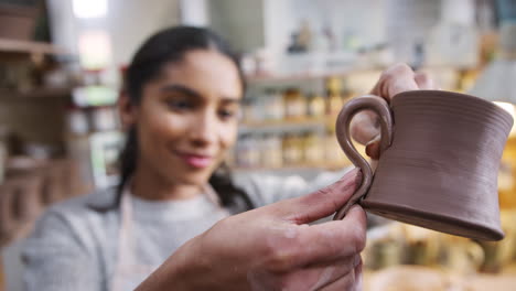 african american woman potter attaching handle to mug in ceramics studio