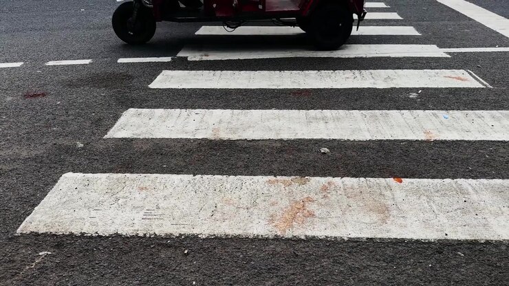 Low angle tracking view of a painted pedestrian crossing on an asphalt road in an urban environment during daytime