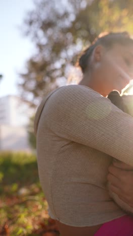 woman cuddling a pug in a park