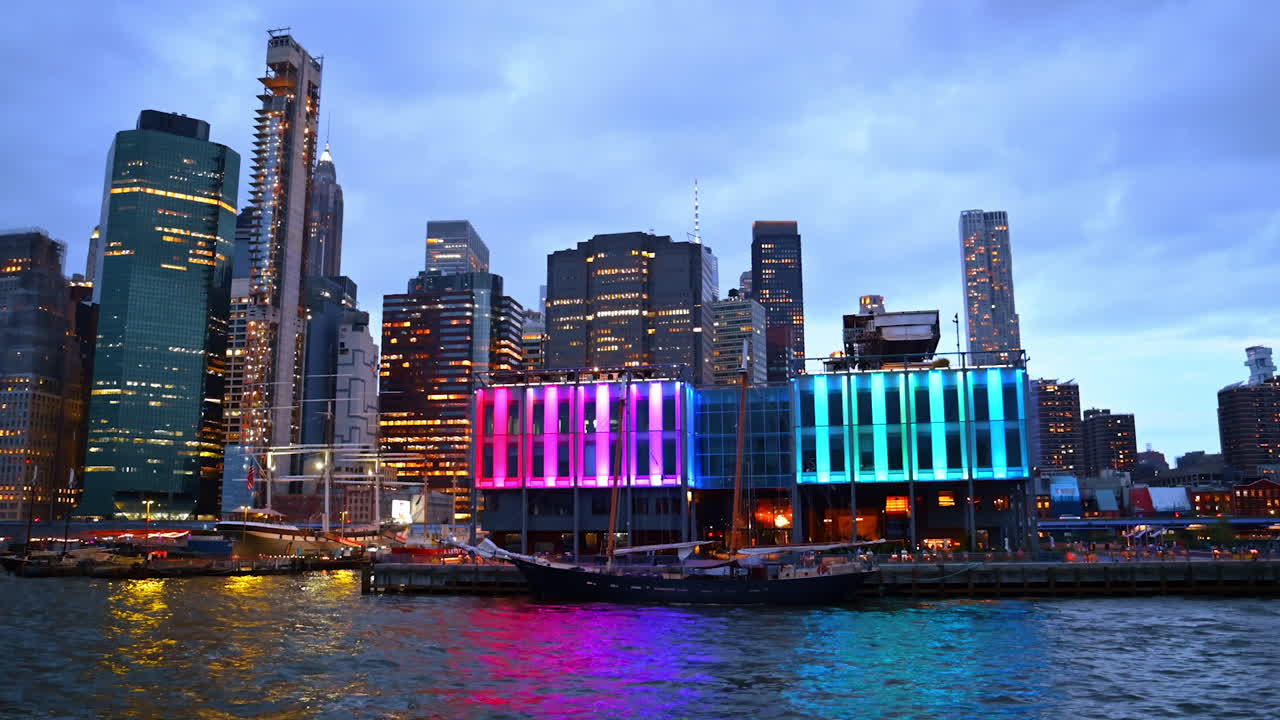 Colorful waterfront view of Manhattan skyline. The Manhattan waterfront shines with bright neon lights and skyscrapers reflecting over the East River