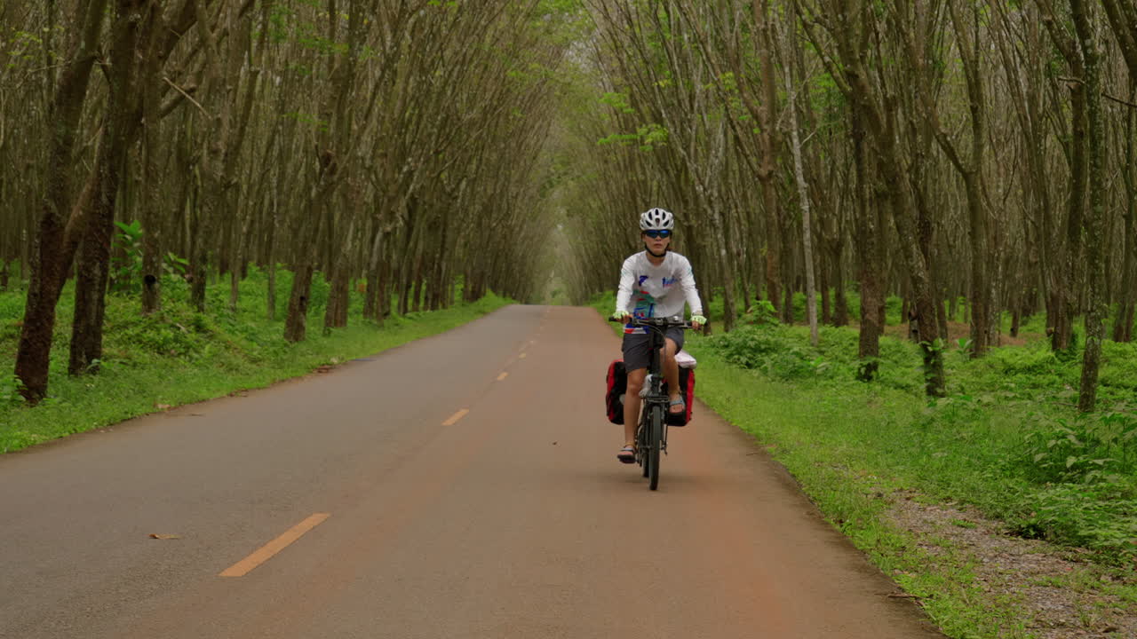 Frontal view woman cyclist in tropical southeast asia jungle bikepacking