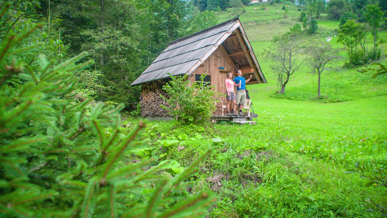 Walking wanderer couple near a wooden house in the forest exploring surroundings