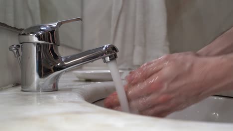 Las-Manos-De-Los-Jóvenes-Se-Lavan-Con-Agua-Del-Grifo-Con-Jabón,-Luego-Se-Enjuagan-Y-Se-Limpian-Con-Una-Toalla-De-Tela-Blanca---Toma-Estática-De-Primer-Plano-De-Vista-Lateral-4k