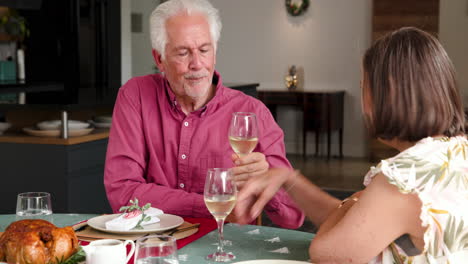 at christmas, senior couple enjoying holiday dinner, sharing wine and conversation at home