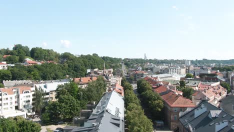 side aerial drone shot of kaunas city old town and savanoriai prospect street while vechiles are moving up the hill