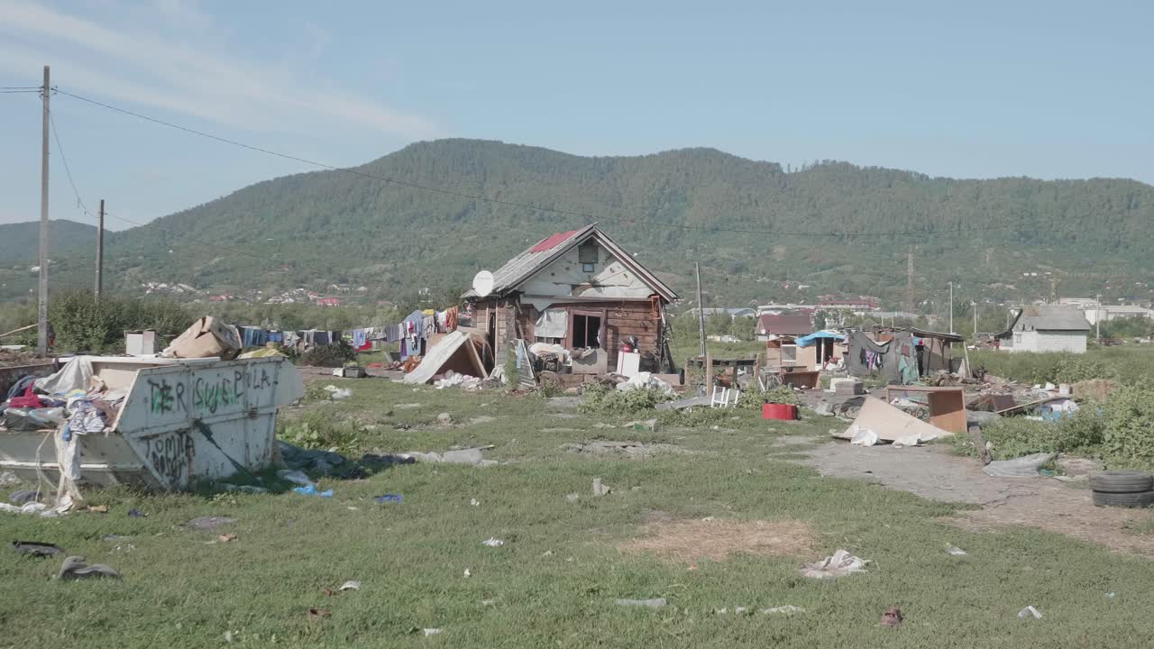 A panning shot reveals makeshift shacks, laundry lines, and piles of garbage in the Pirita informal settlement in Romania, illustrating extreme poverty and marginalization.