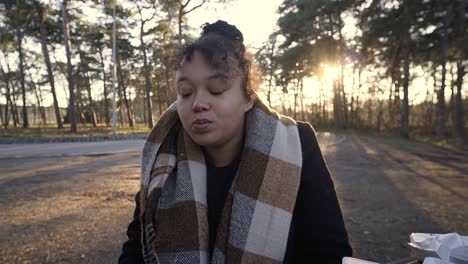 Portrait-shot-of-a-black-woman-eating-some-belgian-fries-as-picknick-in-the-park