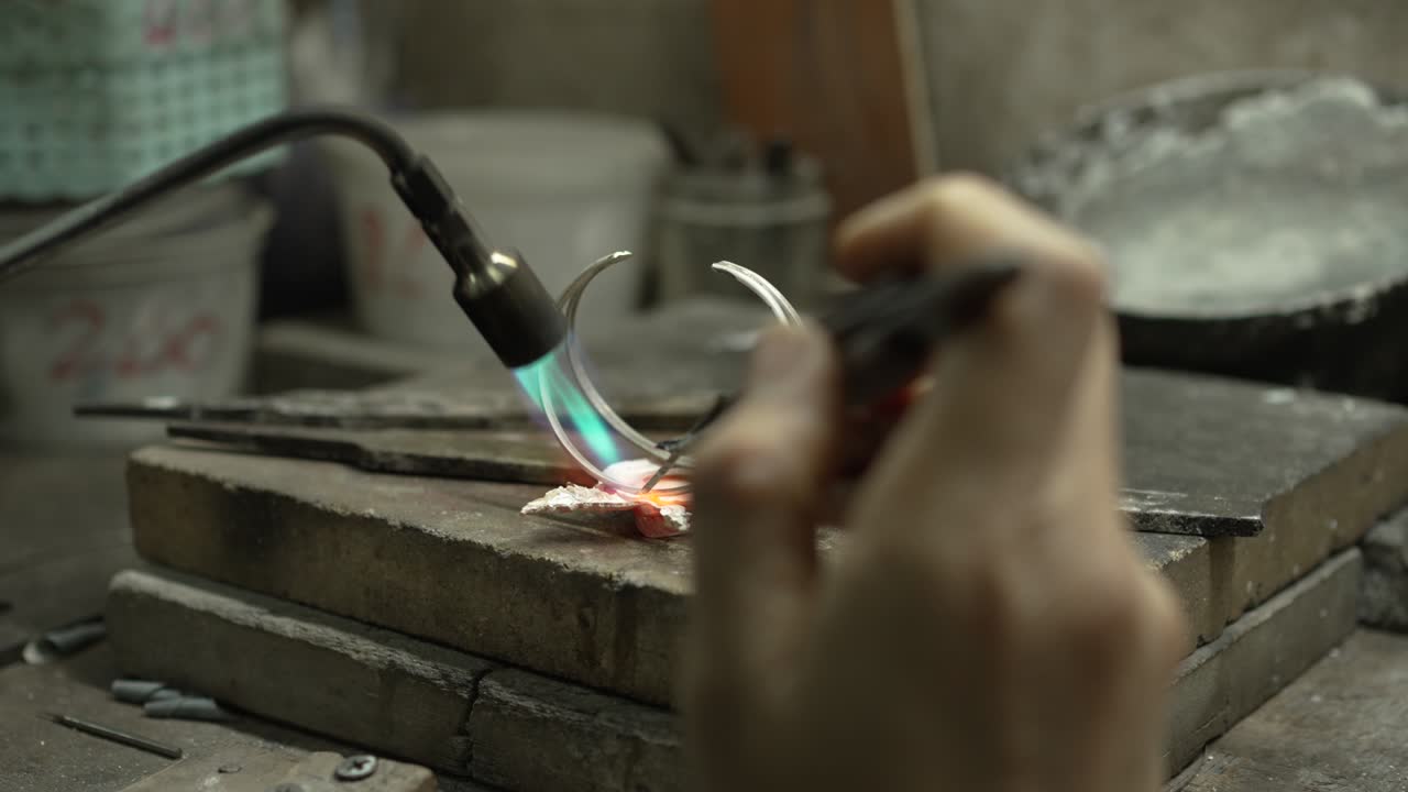 Gioielliere al lavoro in gioielleria. Banco da lavoro per la creazione di gioielli artigianali con strumenti professionali. Primo piano degli strumenti. Thailandia.