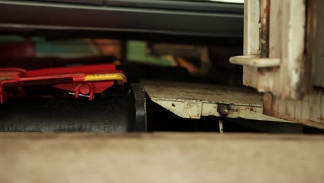 Close-up-of-a-car-on-a-hydraulic-lift-in-a-workshop,-detailing-the-lift-mechanism-and-tire