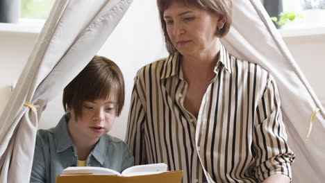 teenager reading book with the help of her mother