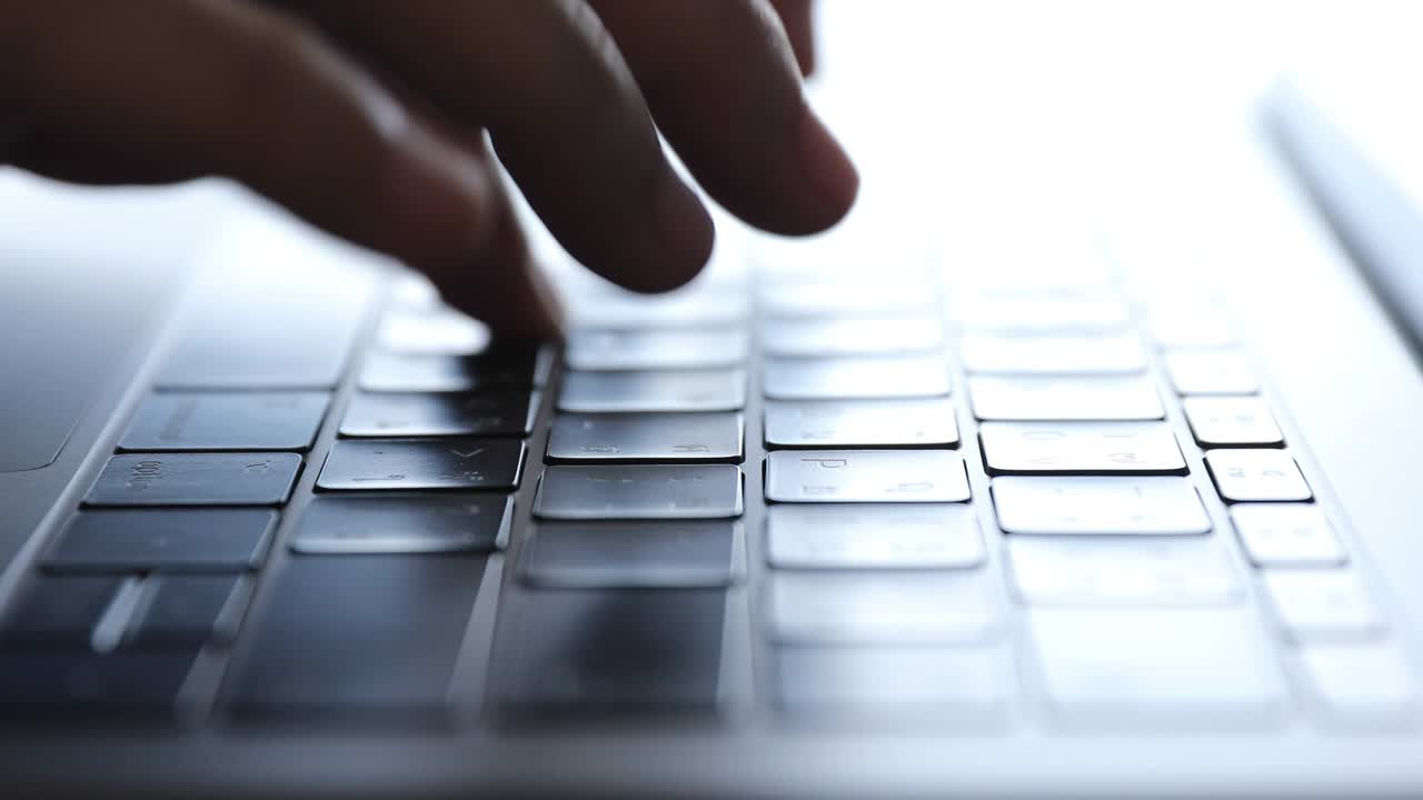 Close up of man hands typing and enter key on a laptop computer keyboard, indoors.