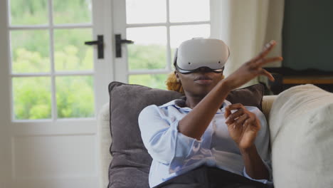 Frau-Entspannt-Sich-Zu-Hause-Auf-Dem-Sofa-Liegend,-Trägt-Ein-VR-Headset-Und-Interagiert-Mit-AR-Technologie