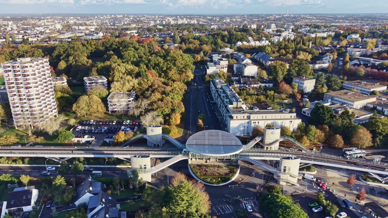 Dronebillede i fugleperspektiv af den moderne La Poterie-metrostation i Rennes. Viser et tog, der ankommer til den højtliggende platform omgivet af efterårstræer. Ideelt til bytransportkoncepter, Frankrig.