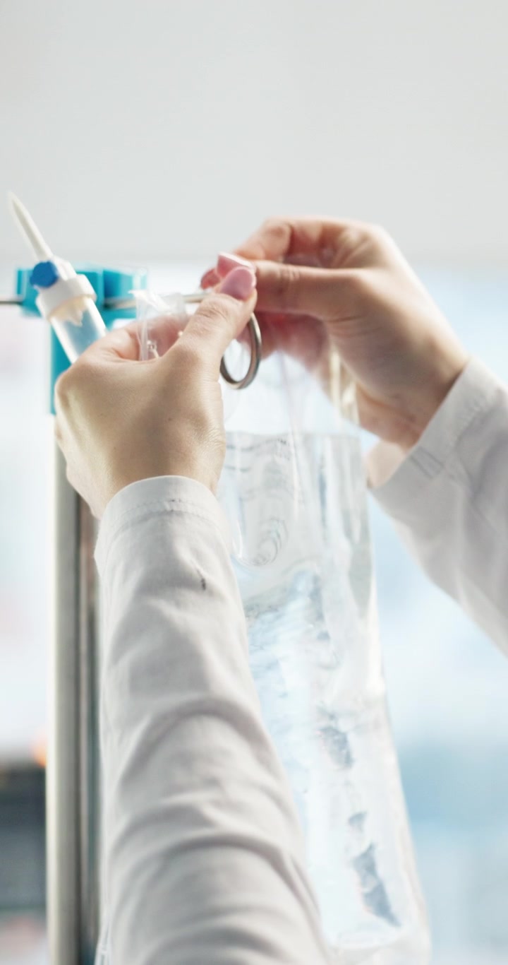 Infermiera che regola una sacca per flebo in una stanza d'ospedale