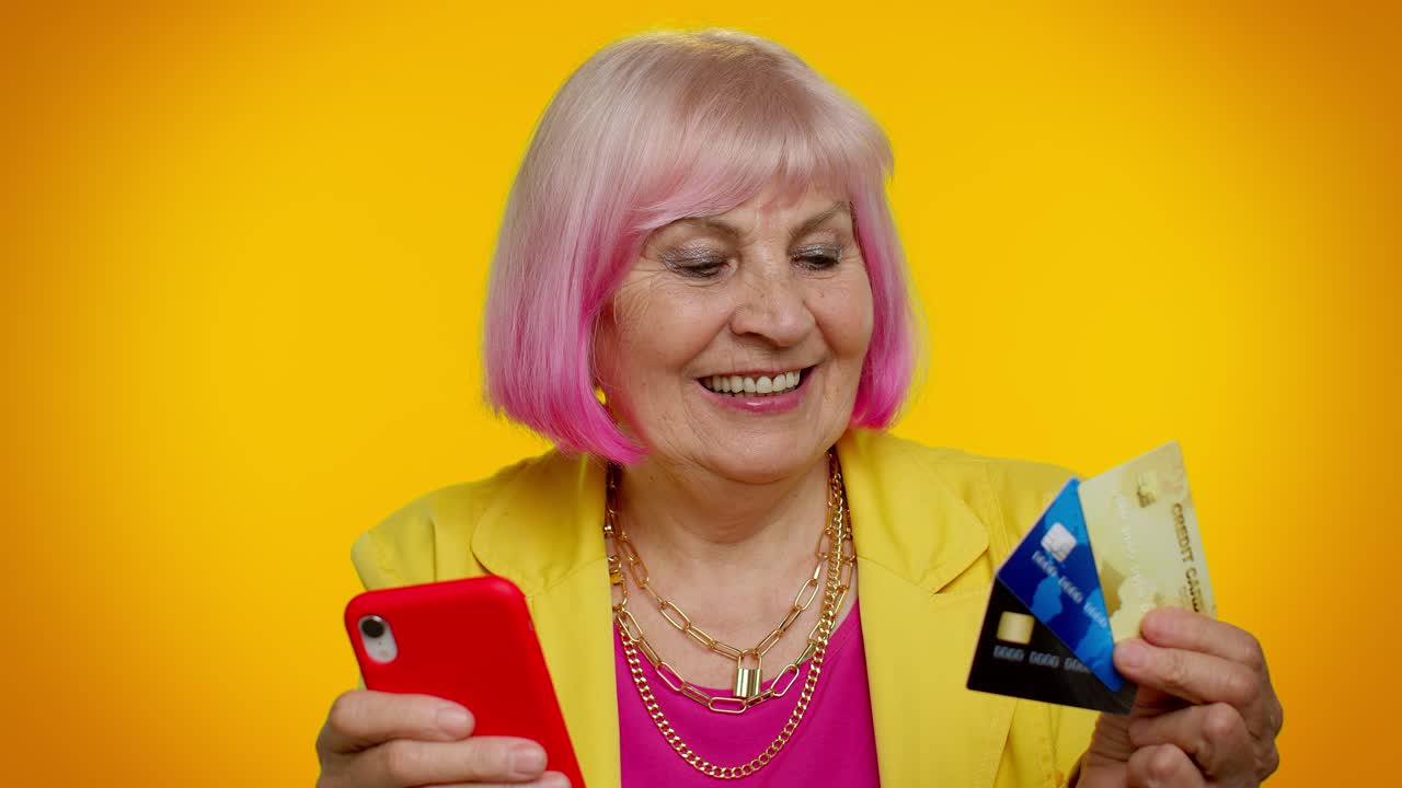 신용 카드, 플라스틱 카드 및 휴대 전화 구매를 사용하여 온라인 쇼핑을하는 노인 할머니