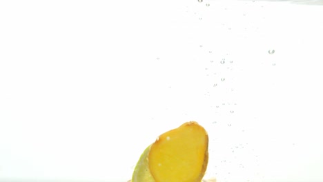 piezas de fruta de mezcla fría caídas en agua, aisladas sobre fondo blanco