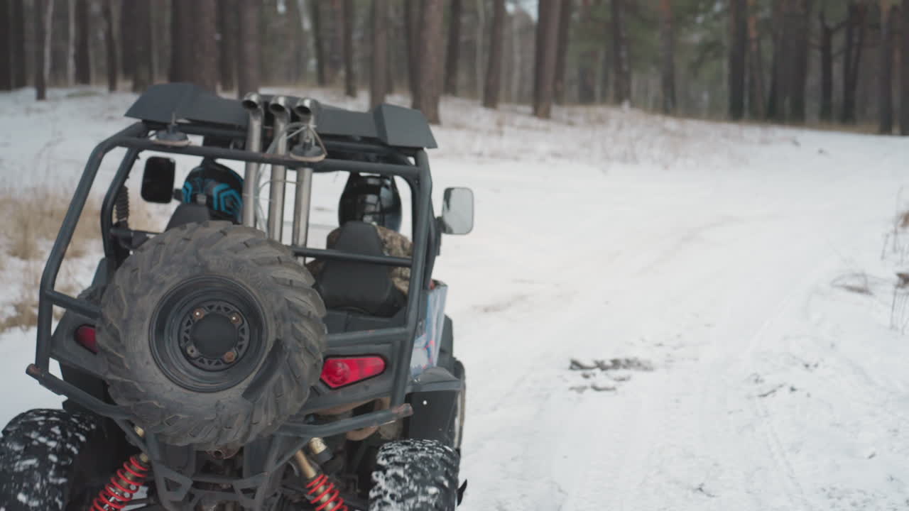 Guida che esamina la mappa per un viaggio invernale in quad. Il conducente con il casco prepara l'UTV per il percorso nella foresta innevata. Ruota di scorta e mappa controllate prima di iniziare una tranquilla escursione invernale in quad sulla neve.