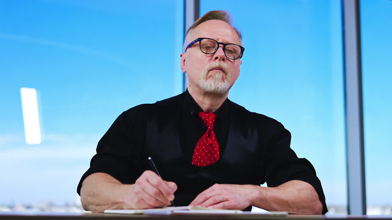 Focused hard-working man sits at desk in office. Businessman writing in the notebook. Low angle view.