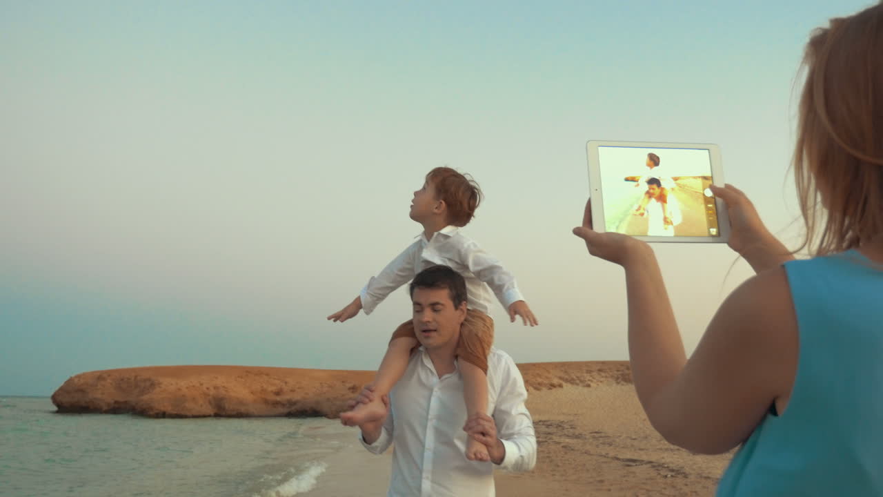 madre con pad disparando padre e hijo en la playa