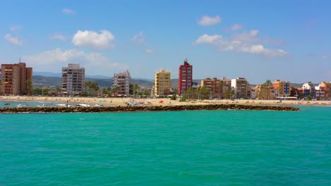 Boat-POV-Aerial-view-of-the-coastline-of-Torrenostra-in-Torreblanca,-Castellon,-Spain