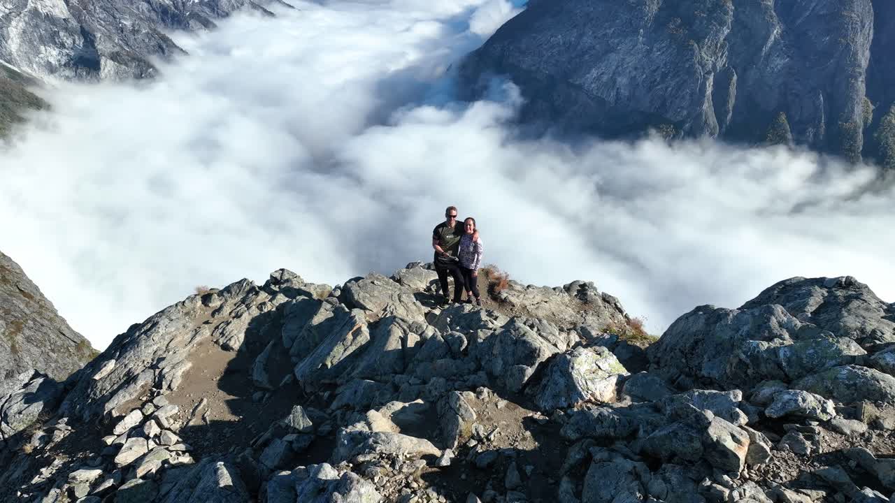 Ripresa con dolly zoom di una coppia in piedi al punto panoramico di Bakkanosi, che si affaccia sul fiordo con nuvole e nebbia molto più in basso