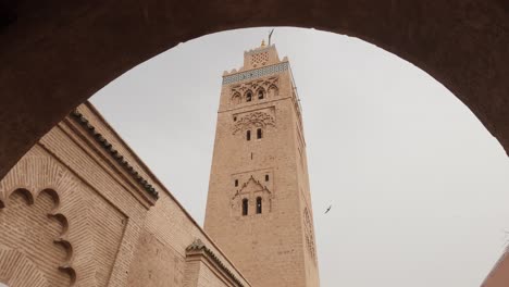 mirando hacia arriba a la torre de la mezquita de koutoubia debajo de la silueta del arco de la calle marroquí