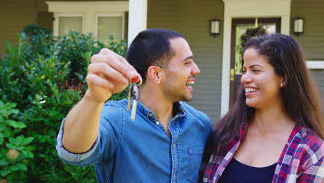 Retrato-De-Una-Pareja-Sosteniendo-Las-Llaves-De-Su-Nuevo-Hogar-Al-Mudarse-En-El-Día