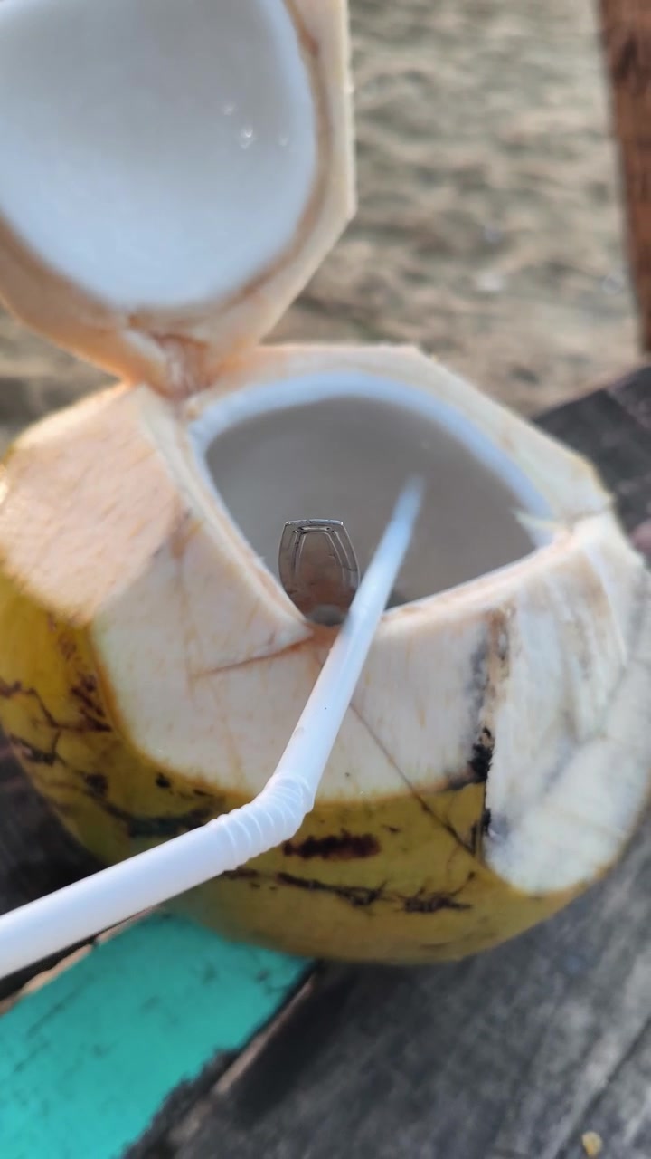 Fresh Coconut Drink with Straw on a Tropical Beach
