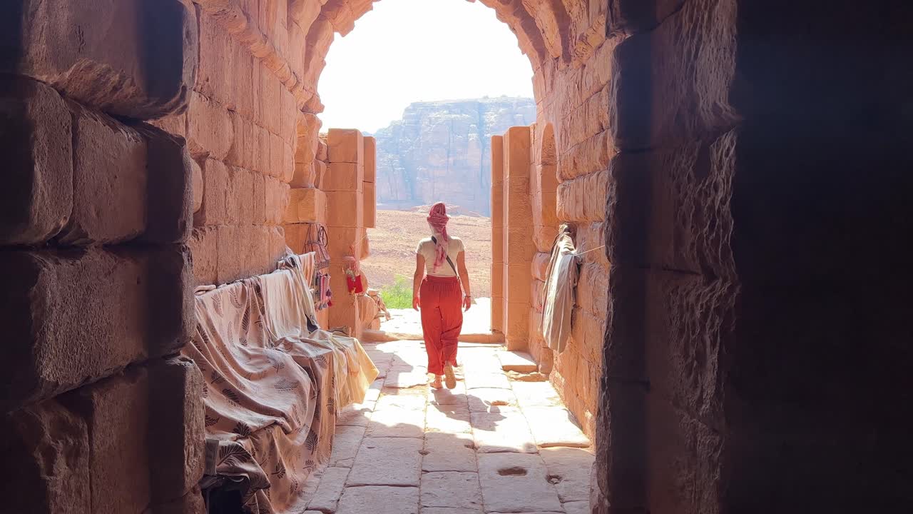 mujeres altas caminando en petra en wadi musa, cerca del tesoro de jordania sin otras personas alrededor saliendo de una puerta en petra en 4k