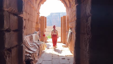 Tall-Women-walking-in-Petra-in-Wadi-Musa,-close-to-the-Treasury-of-Jordan-with-no-other-people-around-exiting-a-door-into-Petra-in-4K