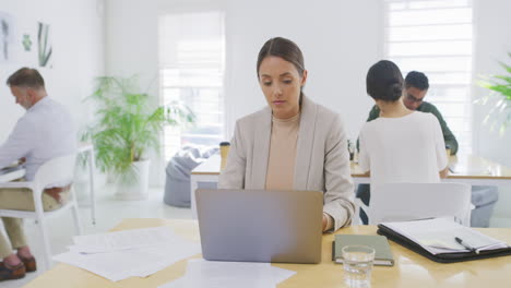 Geschäftsfrau,-Die-Am-Laptop-Mit-Papierkram-Arbeitet