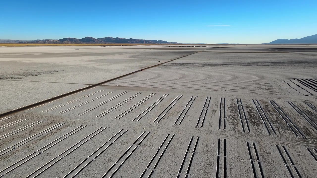 Una griglia industriale si estende nella salina di Salinas Grandes con le lontane catene delle Ande sotto un cielo azzurro limpido