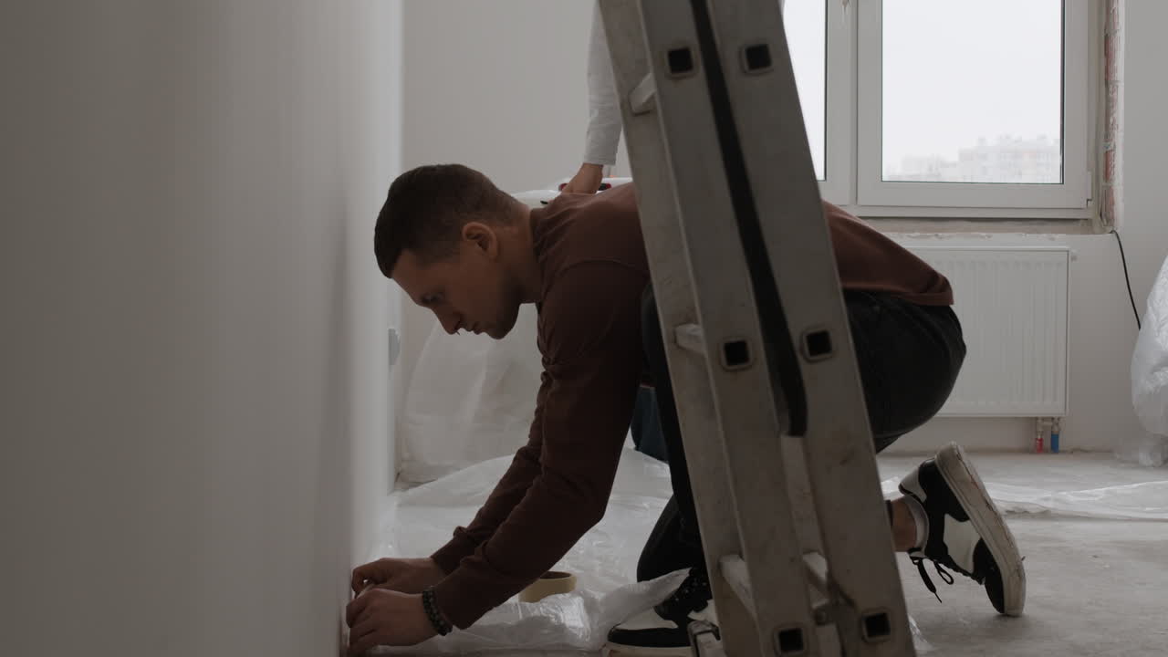 Young Couple Renovating Their Home: Painting and Preparing Walls