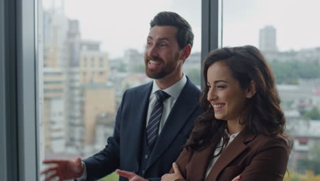 Two-smiling-colleagues-talking-in-office-corridor-at-work-break-close-up.