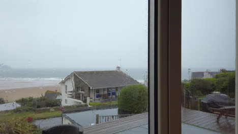 gotas de lluvia cayendo por una ventana de vidrio con vista al mar en cámara lenta