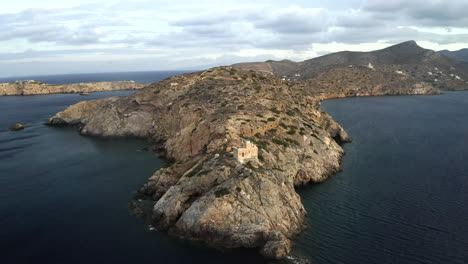 Drone-aerial-footage-of-lighthouse-on-peninsula-in-the-Mediterranean-on-the-island-of-Ios,-Greece