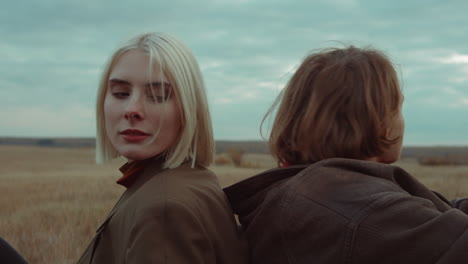 Couple-Sitting-Back-to-Back-on-Autumn-Field