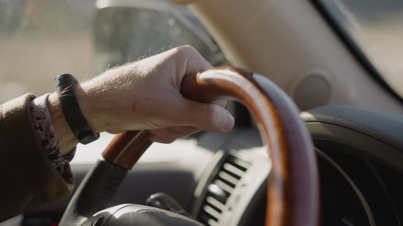 디지털 손목 시계를 가진 젊은 남자가 도로를 따라 자동차를 운전합니다.