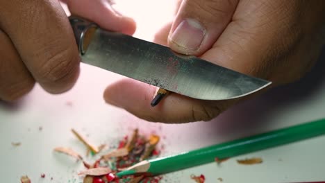 Footage-of-hands-slowly-sharpening-a-pencil-and-some-coloured-pencils-with-a-sharp-knife